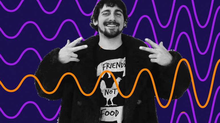 DJ Keano smiles and makes peace signs to the sides of his shoulders