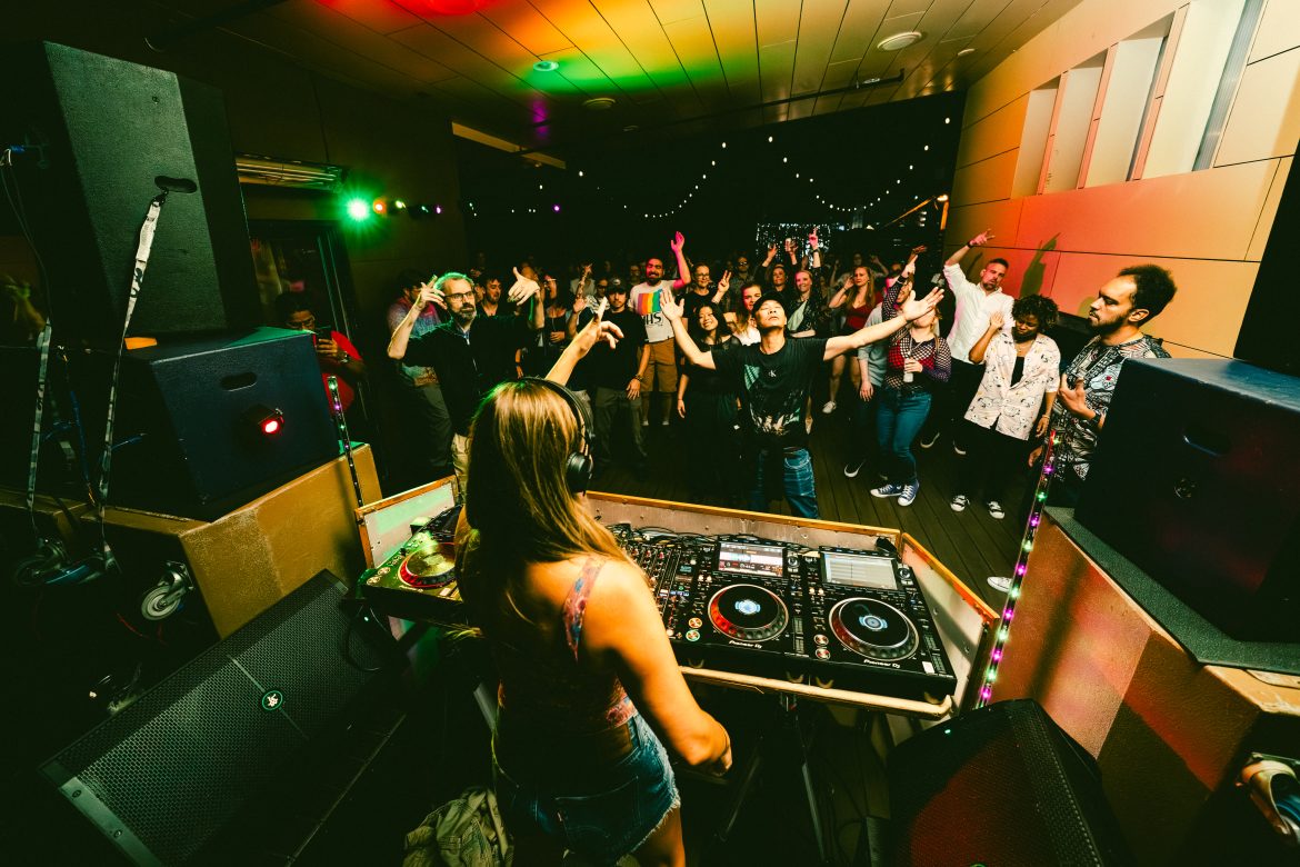 Woman DJs on the deck at Monkey Loft to a dancing crowd